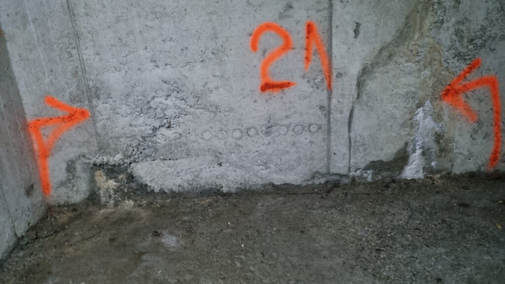 Prodor vode pri dnu betonskog zida sa označenim mestima sanacije